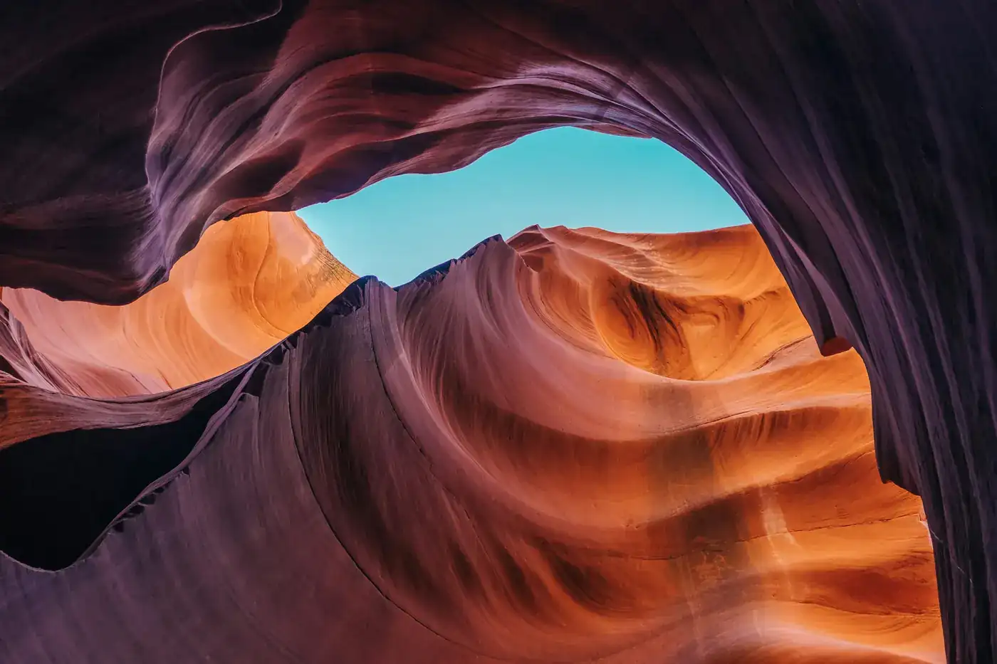 Ein Sandstein-Canyon, der unter einem Stück blauen Himmels orange und violett leuchtet.